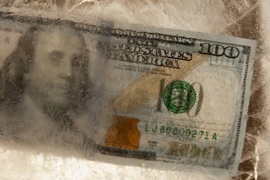 Yeni 100 dolarlık banknot buz tabakasının altında, küresel ekonomik kriz konsepti veya doların dünya piyasasına düşüşü