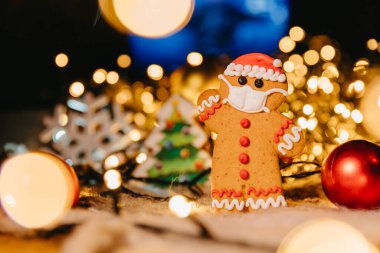 Koronavirüs salgınında yeni yıl ve Noel kutlaması, odaklanmamış ışıklarla kavramsal arka plan ve yüz maskeli kızıl adam, boşluğu kopyala