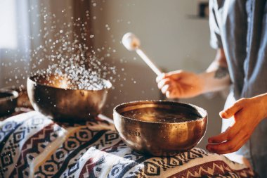 Bir adam şarkı kasesi tutuyor ve Tibet kasesi çalıyor.