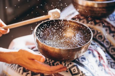 Spa salonunda Nepal Buda bakır kasesi. Genç sakallı adam masaj terapisi yapıyor. Spa 'da şarkı söylüyor. Ses terapisi, dinlenme, meditasyon, sağlıklı konsept.