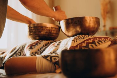 Spa salonunda Nepal Buda bakır kasesi. Genç sakallı adam masaj terapisi yapıyor. Spa 'da şarkı söylüyor. Ses terapisi, dinlenme, meditasyon, sağlıklı konsept.
