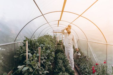 Bahçe yataklarının arasında vazolar ve diğer bitkilerle duran genç ve çekici bahçıvanın fotoğrafı. Metnin için boşluk kopyala