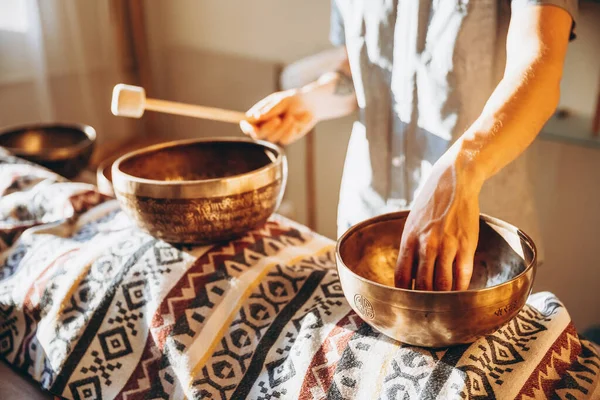 Nepal Buddha copper singing bowl at spa salon. Young bearded man doing massage therapy singing bowls in the Spa. Sound therapy, recreation, meditation, healthy concept