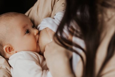 close up portrait of a child who sucks the milk from mother breast. Female breastfeeding her little daughter in her arms clipart