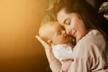 Kollarında anne ve yeni doğan kızın otantik portresi. Bir kadın bir çocuğa gülümser, sarılır ve öper, konuşur ve sevinir, annesinin ve bebeğinin yüzünde mutlu bir gülümseme