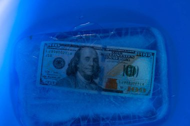 Yeni 100 dolarlık banknot buz tabakasının altında, küresel ekonomik kriz konsepti veya doların dünya piyasasına düşüşü