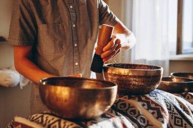 Spa salonunda Nepal Buda bakır kasesi. Genç sakallı adam masaj terapisi yapıyor. Spa 'da şarkı söylüyor. Ses terapisi, dinlenme, meditasyon, sağlıklı konsept.