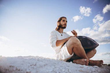 Sıcak çölün ortasında oturan bir müzisyen. İnsansız büyük bir alan. Genç bir hipster için favori hobi.