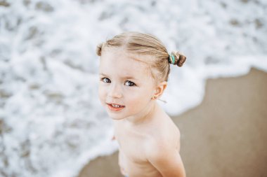 Okyanusun kenarında poz veren güzel ve anlamlı küçük bir kız.