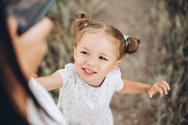 Anne kızının yanına oturur ve parmaklarının ucunda onunla oynar.