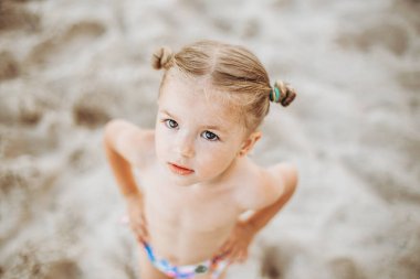 Okyanusun kenarında poz veren güzel ve anlamlı küçük bir kız.