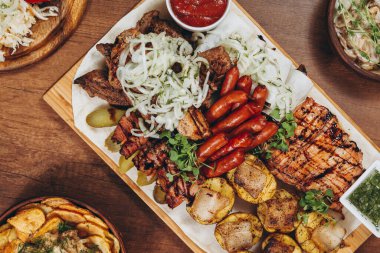 Çeşit çeşit lezzetli ızgara et, sebze ve kırsal masada otlar.