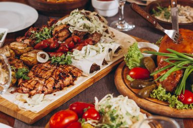 Çeşit çeşit lezzetli ızgara et, sebze ve kırsal masada otlar.