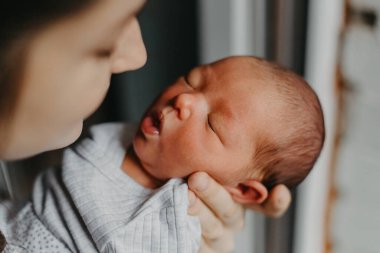 Annesinin kollarında yeni doğmuş bir bebeğin ev fotoğrafları. Seçici odak, gürültü etkisi
