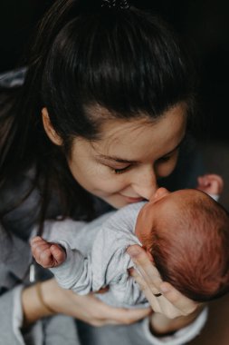 Annesinin kollarında yeni doğmuş bir bebeğin ev fotoğrafları. Seçici odak, gürültü etkisi