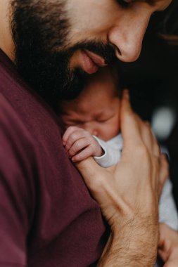 Yeni doğmuş bir bebeğin babasının kollarında çekilmiş fotoğrafları. Seçici odak, gürültü etkisi