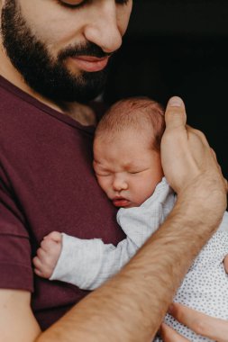 Yeni doğmuş bir bebeğin babasının kollarında çekilmiş fotoğrafları. Seçici odak, gürültü etkisi