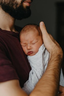 Yeni doğmuş bir bebeğin babasının kollarında çekilmiş fotoğrafları. Seçici odak, gürültü etkisi