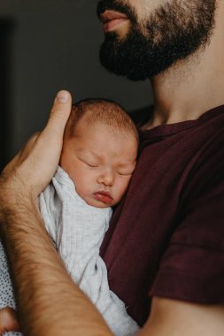 Yeni doğmuş bir bebeğin babasının kollarında çekilmiş fotoğrafları. Seçici odak, gürültü etkisi
