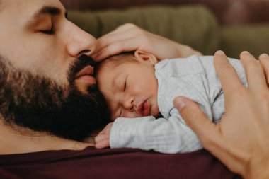 Yeni doğmuş bir bebeğin babasının kollarında çekilmiş fotoğrafları. Seçici odak, gürültü etkisi