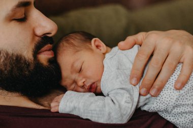 Yeni doğmuş bir bebeğin babasının kollarında çekilmiş fotoğrafları. Seçici odak, gürültü etkisi