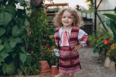 Ukrayna folkloru işlemeli bir elbise giymiş, çiçekli bir fotoğraf için poz veren tatlı bir kızın portresi.