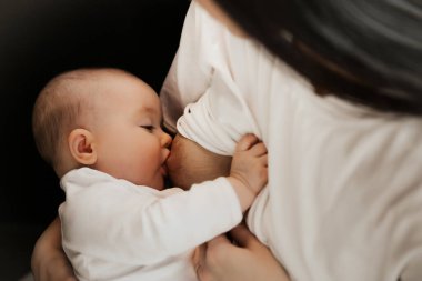 Genç bir kadın bebeğini emziriyor.