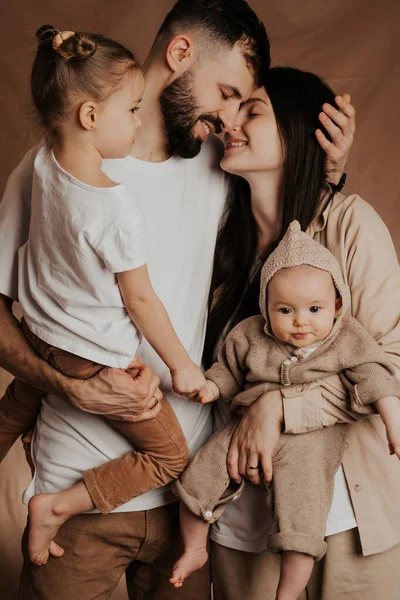 モノクロの背景で撮影された腕の中に2人の子供を持つ若い家族の肖像 — ストック写真
