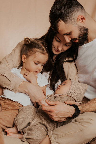 Portrait of a young family with two children in his arms photographed on a monochrome background