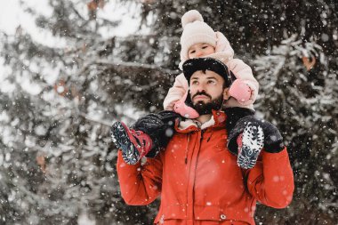 Sevgi dolu bir aile! Babası ve bebeği dışarıda oynuyorlar ve sarılıyorlar. Karlı kış yürüyüşüne çıkmış şirin bir çocuk ve baba. Buz mevsimi kavramı.