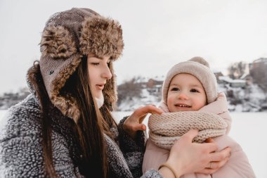 Sevgi dolu bir aile! Anne ve kız doğada karlı kış yürüyüşlerinde eğleniyor, gülüyor ve eğleniyorlar. Buz mevsimi.