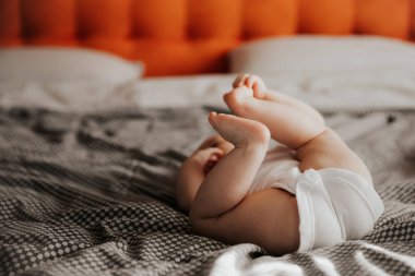 Odadaki yatakta uzanıp oynayan, pencereden gün ışığıyla çekilmiş güzel bir bebek.