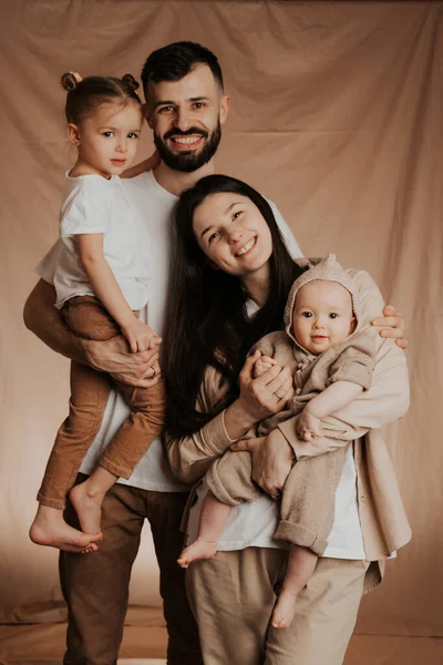 モノクロの背景で撮影された腕の中に2人の子供を持つ若い家族の肖像 — ストック写真