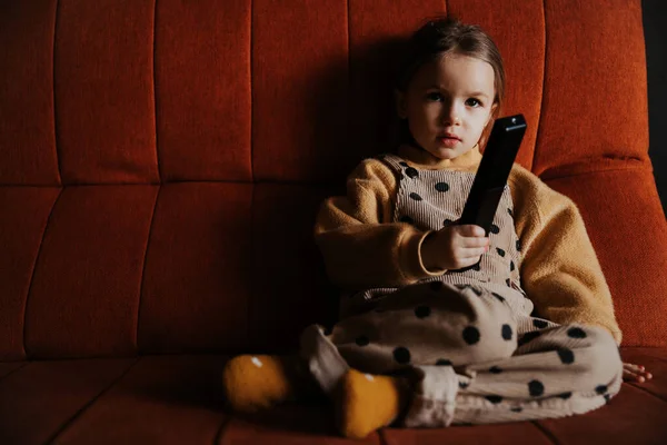 Маленькая Девочка Смотрит Телевизор Лежащий Диване Пультом Дистанционного Управления Руке — стоковое фото