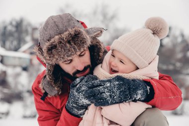 Sevgi dolu bir aile! Babası ve bebeği dışarıda oynuyorlar ve sarılıyorlar. Küçük çocuk ve babası karlı bir kış yürüyüşünde. Uzun zamandır beklenen ilk kar yağışının konsepti. Boşluğu kopyala