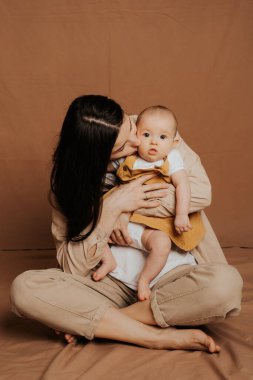 Şık bir anne ve yeni doğmuş kızının bir stüdyo taklidiyle evde çekilmiş şık elbiseli portresi.