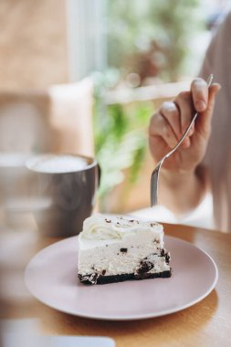 Bir tabakta duran beyaz bir kekin fotoğrafı müşterinin tattığı bir masada.