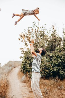 Baba, çocuğu elleriyle çok yükseğe fırlatır.