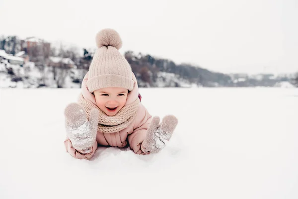 Portrait of a girl playing in the snow during a winter walk and playing snowballs, rolling and skating in the snow