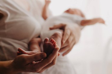 Yeni doğmuş bir bebeğin bacakları ebeveynlerin ellerinde.