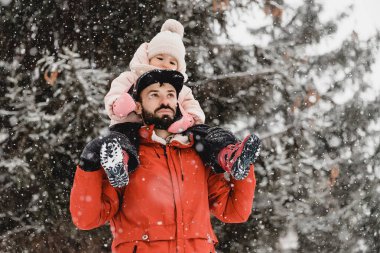 Genç şık sakallı baba ve küçük kızı kış tatilinde. Baba oğlunu parka geri götürüyor. Mutlu, neşeli bir aile. Mutlu, neşeli bir aile.