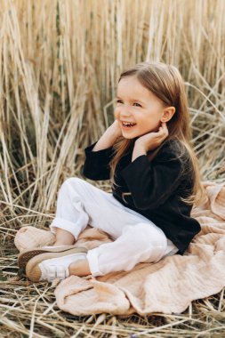 Çok mutlu, gülümseyen ve pozitif küçük bir kız. Sahada yürürken fotoğraf için poz veriyor.