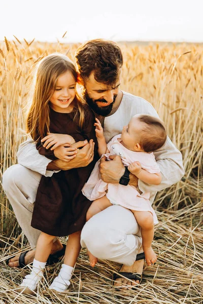 彼の小さな娘の腕の中で幸せな若い父親 父と2人の娘はフィールドで撮影されています 幸せなウクライナの家族 — ストック写真