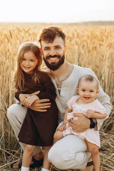 彼の小さな娘の腕の中で幸せな若い父親 父と2人の娘はフィールドで撮影されています 幸せなウクライナの家族 — ストック写真