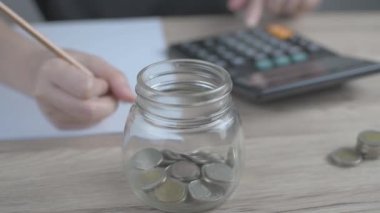 Kadın, aylık gelir ve giderleri hesaplamak için aylık tasarruflarını hesaplamak üzere hesap makinesine basıyor.