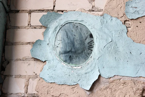 The mirror is concreted into a brick wall with the edges of which are dilapidated blue paint.