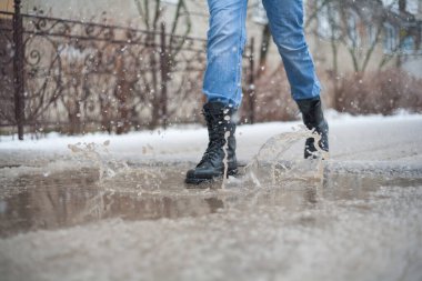 Şehirdeki su birikintilerinde asker botları, siyah bağcıklı botlar ve ıslak hava, şehirde yürüyüş ayakkabıları, yağmur, kar ve dolu, şehirde güvenilir ayakkabılar giymek daha iyidir..