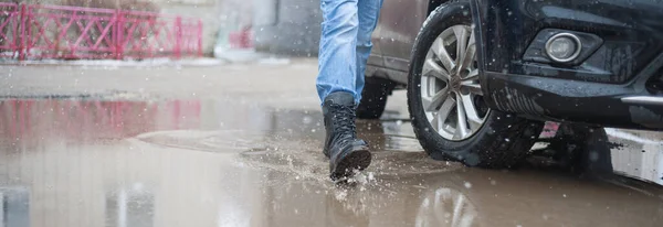 in army boots on puddles in the city, black lace-up boots and wet weather, trekking shoes in the city, rain, snow, and hail in the city, it is better to go in reliable shoes.