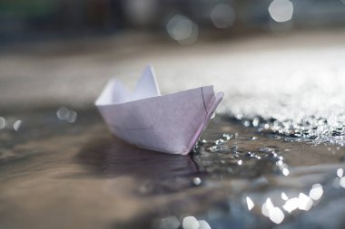 Kağıttan bir tekne şehirdeki bir dere boyunca yelken açar.