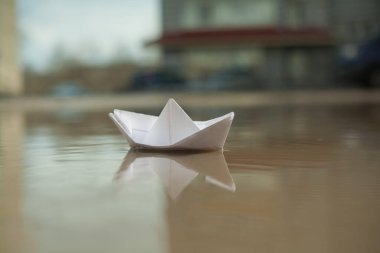 Kağıttan bir tekne şehirdeki bir dere boyunca yelken açar.